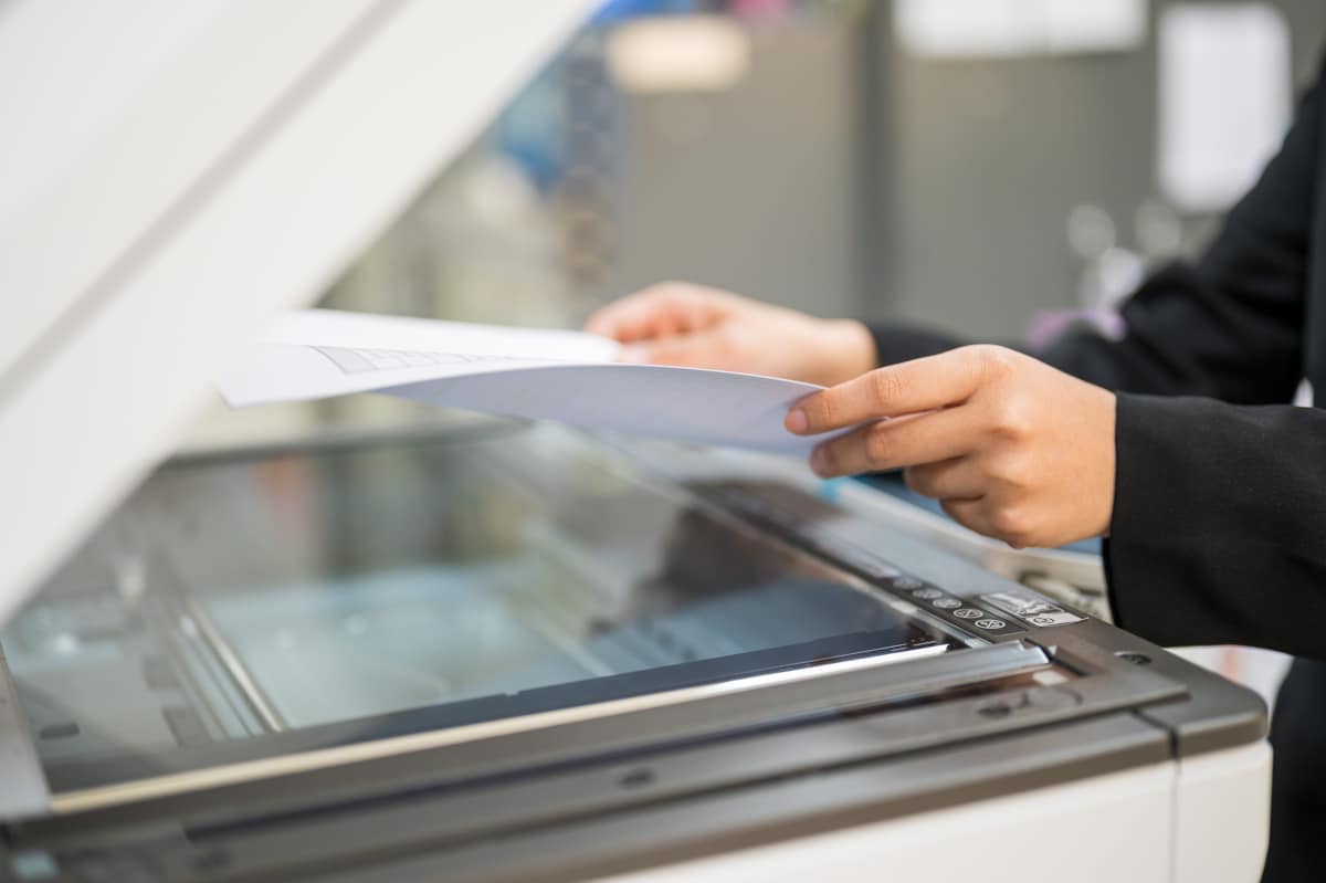 Person placing a document on the glass of an office copier to make a copy